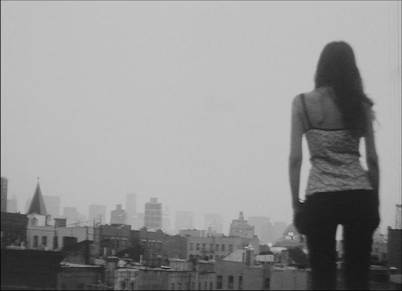 Woman standing with back to camera, looking out at a city skyline